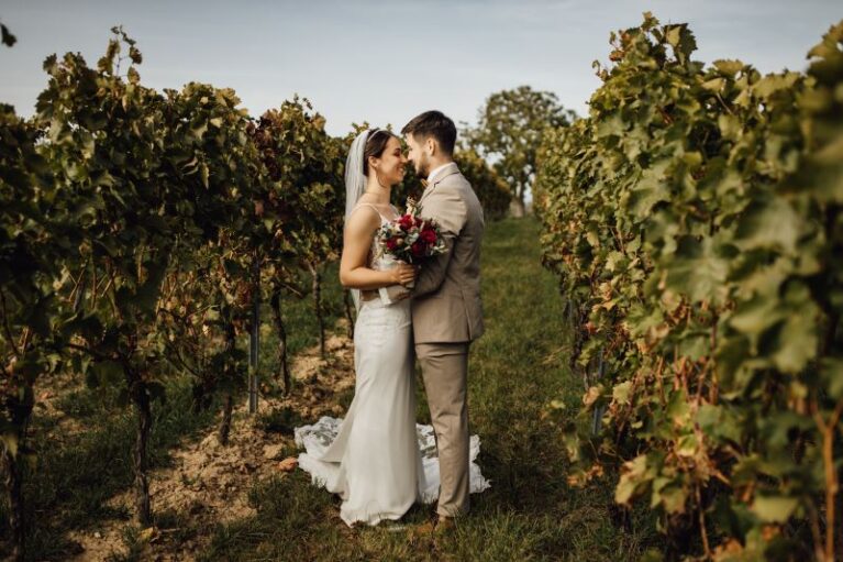 Brautpaar im Weinberg, umgeben von Reben, romantische Hochzeitsatmosphäre.