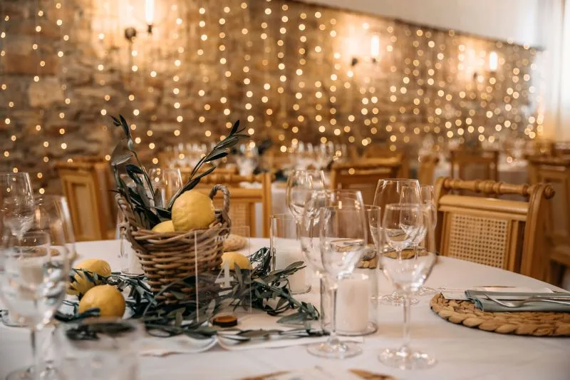 Festlich gedeckter Tisch mit Zitronen und Olivenzweigen, umgeben von warmen Lichterketten für eine elegante Veranstaltung.