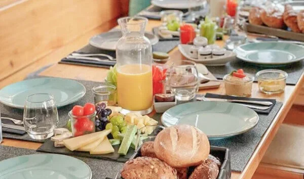 Frühstückstisch der Hochzeitslocation Sankt Gereon mit Brötchen, Käse, Obst und Orangensaft