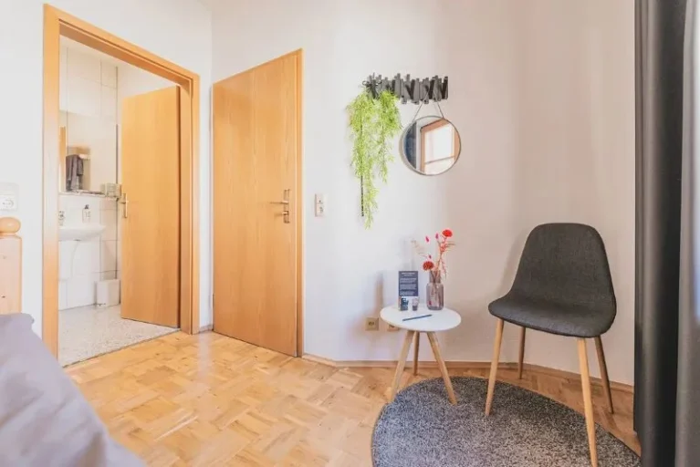 Zimmer der Hochzeitslocation mit Blick durch die Tür ins Bad, gemütlicher Sitzecke und Deko